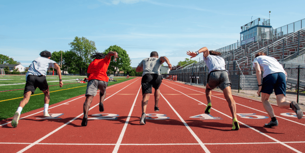 Group of college athletes sprinting on a track field, illustrating the competitive nature of collegiate sports and the impact of Name, Image, and Likeness (NIL) opportunities.