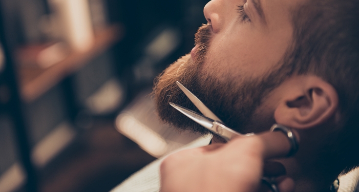 Close up cropped profile photo of a styling of a red beard. So trendy and stylish! Advertising and barber shop concept