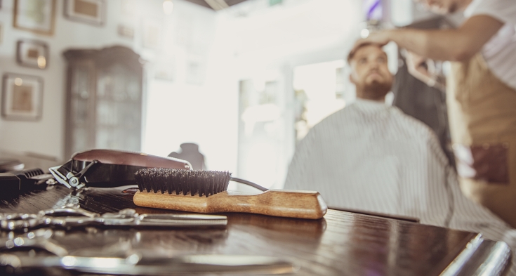 Accesories for cutting on the table in a barbershop and a hairdresser works in the background.