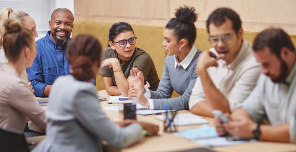 Large group sitting around a table in the boardroom during a meeting.