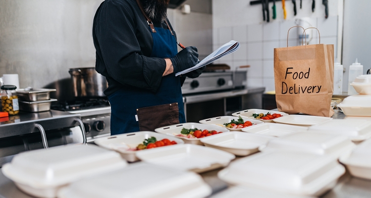 The chef prepares food in the restaurant and packs it in disposable lunch boxes. Food in disposable dishes ready for delivery.